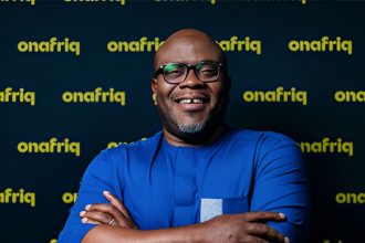 African woman using a smartphone and bank card for digital payments in DR Congo